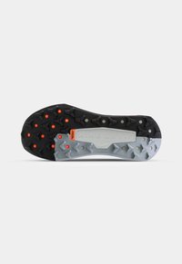 Semelle de chaussure avec sections en caoutchouc noir et gris et crampons de traction orange, conçue pour l'adhérence et la durabilité sur différentes surfaces.