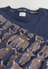 T-shirt blu navy con un motivo arricciato che presenta design di pecore rosa chiaro. Materiale in cotone morbido, scollo rotondo e maniche corte.