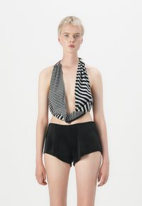 Zwart-witte gestreepte haltertop met een diepe V-hals, gecombineerd met hooggeknoopte zwarte shorts van zachte stof en een aansluitende pasvorm.