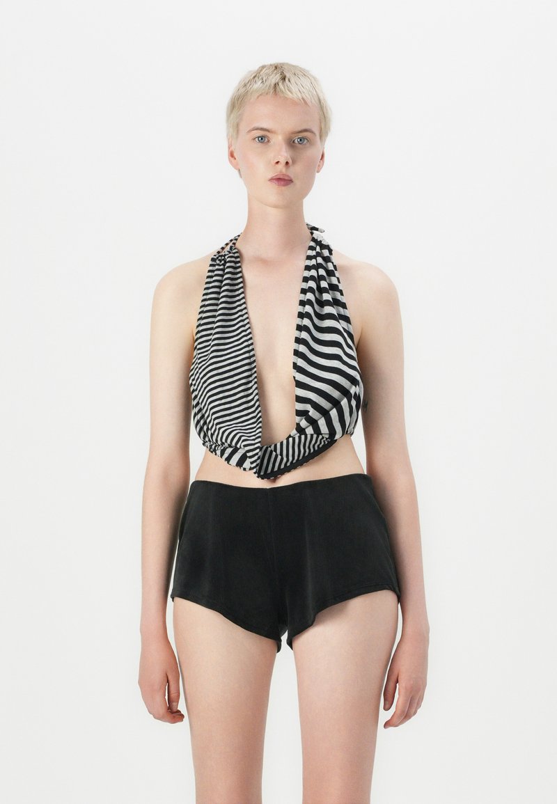 Zwart-witte gestreepte haltertop met een diepe V-hals, gecombineerd met hooggeknoopte zwarte shorts van zachte stof en een aansluitende pasvorm.