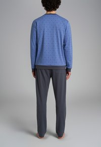 Felpa blu con piccoli motivi, pantaloni grigi, materiale morbido, vestibilità rilassata, polsini e vita a coste, tasche sui pantaloni.