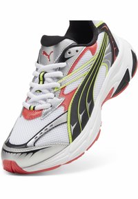Puma Sneakers mit einem atmungsaktiven weißen Mesh-Obermaterial, silbernen Akzenten, roten und schwarzen Überzügen, neongelben Details und weißen Schnürsenkeln.