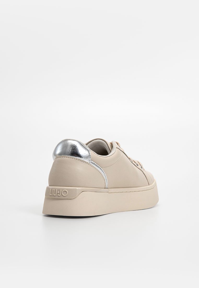 Zapatillas de cuero beige con un acento plateado en el talón y una suela gruesa. Presenta cordones en tono y una sutil marca en el costado.