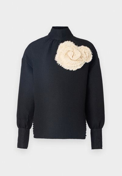 Maglietta nera a maniche lunghe con superficie texture, caratterizzata da una rosa testurizzata di colore crema sulla spalla sinistra. Collo alto, maniche aderenti.