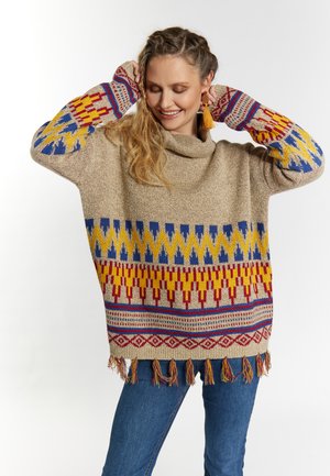 Maglione beige lavorato a maglia con motivi geometrici colorati in rosso, giallo e blu. Presenta un collo a cappuccio e orlo con frange. Vestibilità casual.