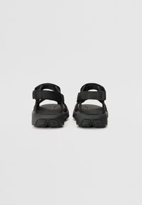 Sorte sandaler med justerbare stofstropper, polstrede såler og en robust tekstureret ydersål, der har et minimalistisk design uden synlige udsmykninger.