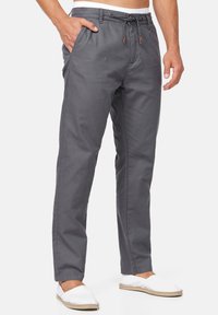 Pantaloni grigi realizzati in tessuto leggero, con vita regolabile tramite coulisse, tasche laterali e design a gamba dritta. Accentuati da cuciture sottili.