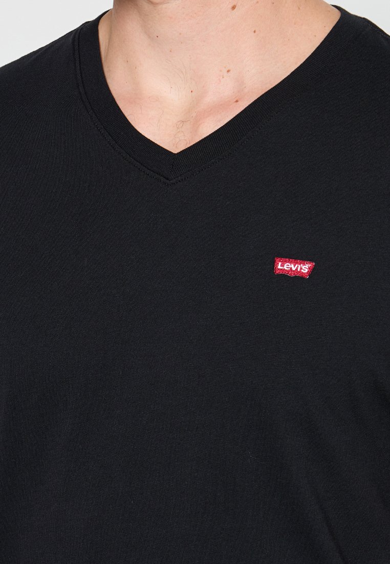 Camiseta negra de cuello en V hecha de algodón suave con un corte ajustado. Presenta un pequeño logotipo rojo de Levi's en el área del pecho izquierdo.