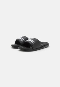 Chanclas negras con un acabado mate suave, que presentan un logo de cocodrilo blanco y una plantilla texturizada. Diseño sencillo, con forma de dedo al aire.