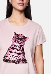 Rosa Baumwoll-T-Shirt mit einem großen schwarzen und rosa Leopardenmuster in der Mitte. Rundhals und kurze Ärmel.