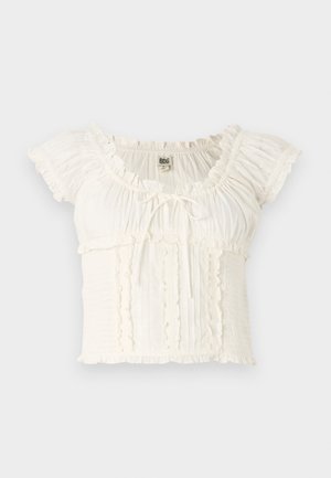 Blusa bianca a maniche corte con bordi arricciati, texture arricciata e un laccio regolabile davanti. Tessuto leggero con dettagli sottili.