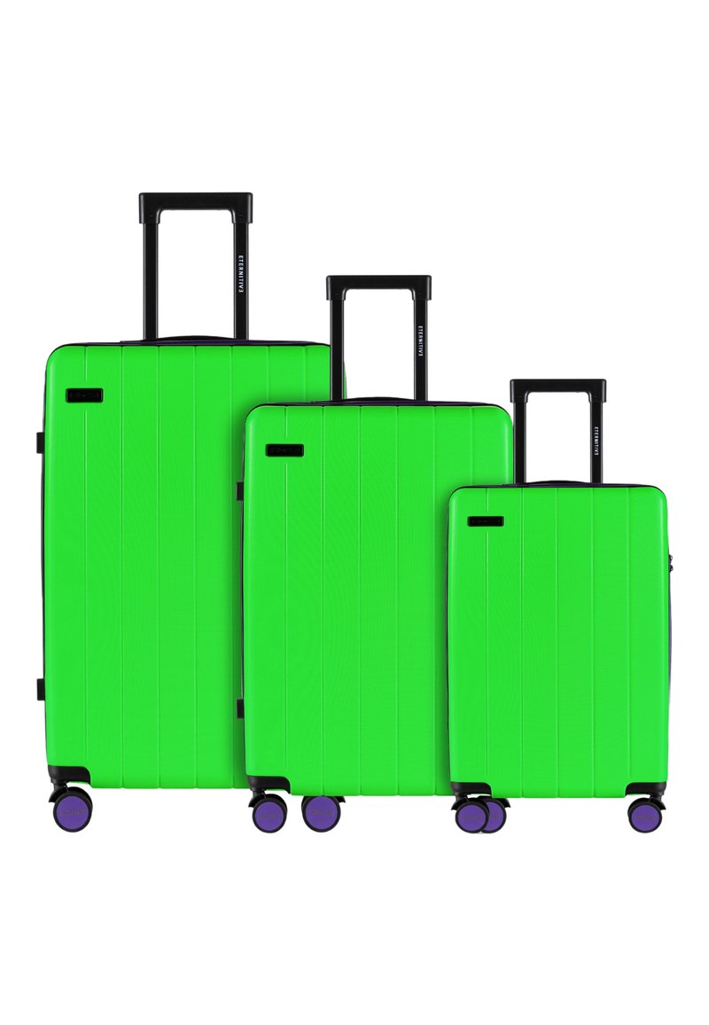 Trzy twarde walizki w intensywnym zielonym kolorze, o różnych rozmiarach, z czarnymi uchwytami i fioletowymi kółkami. Teksturowana powierzchnia z pionowymi liniami.