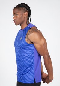 Violet sportinė camisole su tekstūruota mėlyną zebra raštu, be rankovių dizainu ir subtiliu logo detalėmis priekyje, pagaminta iš pralaidaus oro medžiagos.