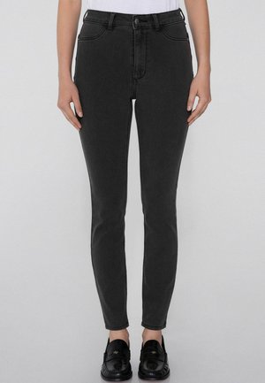 Jeans neri skinny con vita alta, realizzati in denim; presentano cinque tasche e chiusura con bottone; texture liscia e silhouette aderente.