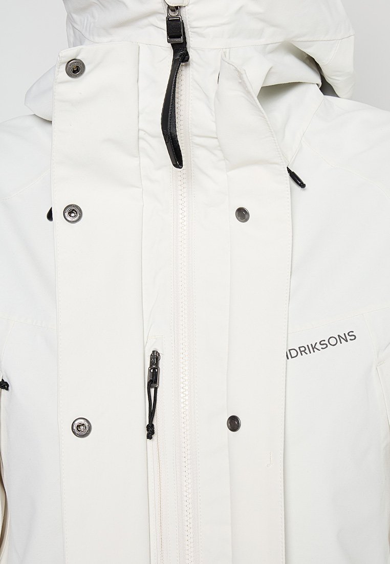 Weiße wasserdichte Jacke mit hohem Kragen, Vorderreißverschluss und schwarzen Akzenten. Verfügt über Druckknöpfe und ein Logo an der Seite.