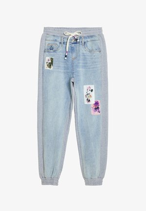 Light blue denim joggers with gray cotton sides, elastic waistband, drawstring, and fabric patches featuring floral designs and a cartoon.