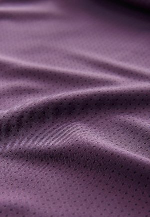 Tissu texturé violet avec une surface lisse et de petits points noirs contrastants, mettant en valeur une qualité douce et fluide ainsi qu'un motif complexe.