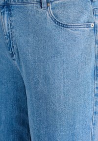 Hellblaue Jeans aus Denim zeichnen sich durch eine glatte Textur, ein klassisches Design mit fünf Taschen und einen dezenten Verblassungseffekt entlang der Oberfläche aus.