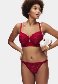 Roter Spitzen-BH und passender Tanga mit floralen Mustern und Schlitz-Detail. Glatte, verstellbare Träger, weicher elastischer Bund.