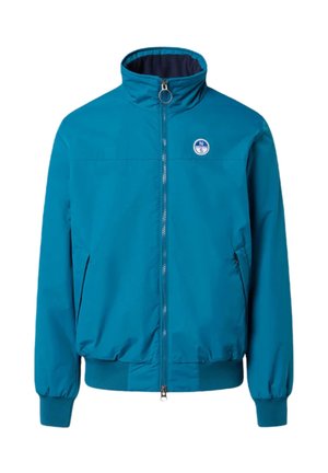 Giacca zip-up turchese con colletto alto, polsini elasticizzati, due tasche laterali e un logo circolare sul petto sinistro. Tessuto liscio e leggero.