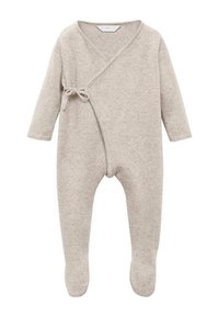 Combinaison pour bébé en tricot beige avec des manches longues, des jambes pieds et une fermeture à nouer sur le côté à l'avant.