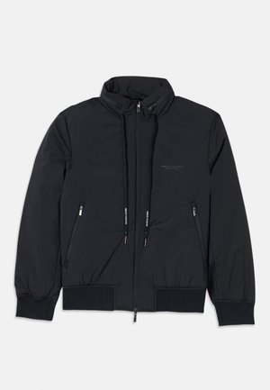 Zwarte geïsoleerde jas met een hoge nek, voorkant met rits, twee zijzakken met rits, elastische manchetten en een trekkoord aan de onderkant. Subtiele logodetails.