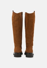 Ruske nubukiseen polvipituiset saappaat, joissa on sileä pinta, takana vetoketjusuljenta ja musta kumipohja.