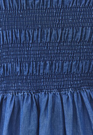 Tela azul con costuras ajustadas de fruncido horizontal que crean una textura elástica y recogida en la sección superior y tela suelta abajo.