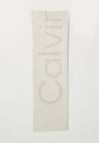 Beige tørklæde med en blød tekstur og et diskret, præget "Calvin Klein" logo samt minimalistisk design. Rektangulær form, let materiale.