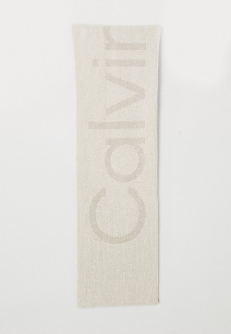 Beige tørklæde med en blød tekstur og et diskret, præget "Calvin Klein" logo samt minimalistisk design. Rektangulær form, let materiale.