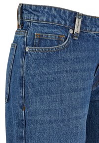 Jeans iz jeansa v srednji modri barvi z teksturirano tkanino, ki imajo oranžno šivanje, sprednji žep in oznako blagovne znamke na pasu.