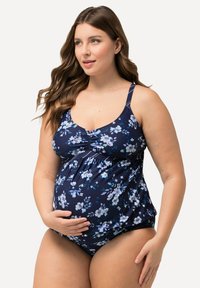 Maillot de bain de maternité bleu marine avec un motif floral. Comprend un tissu froncé au niveau de la poitrine et des bretelles réglables, conçu pour le confort.