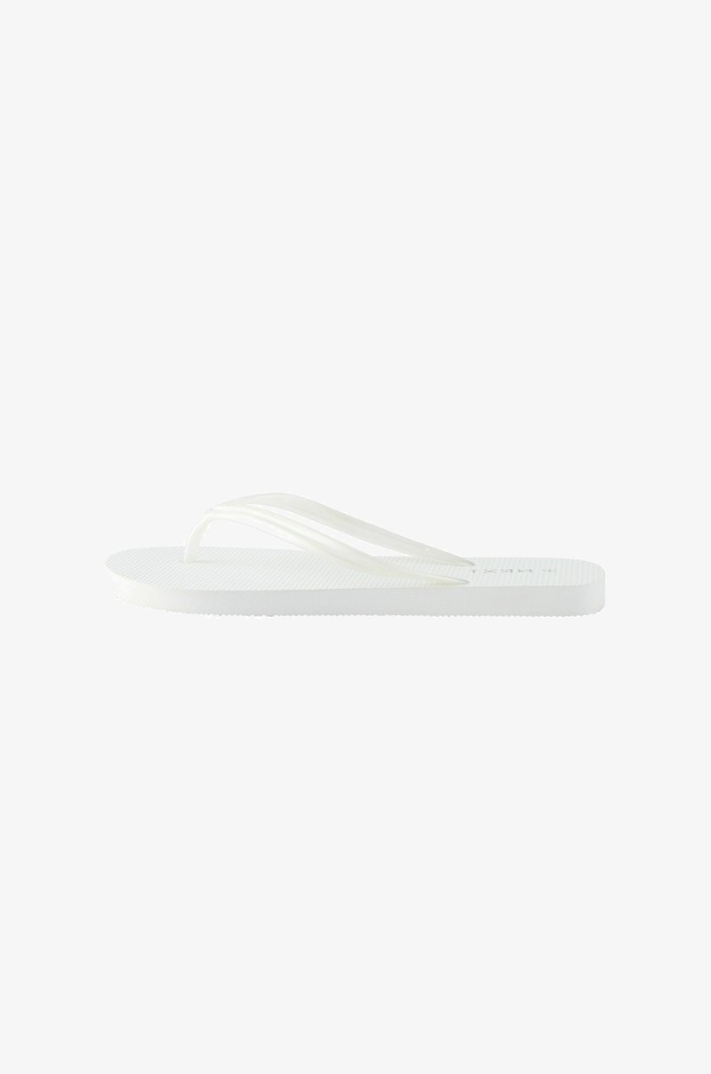 Tongs blanches avec une semelle texturée, dotées de deux fines lanières. Le design est minimaliste et fabriqué en matériau ressemblant au caoutchouc.