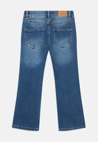 Blue denim flared jeans with a smooth texture, featuring two back pockets and a leather patch on the waistband with brand details.