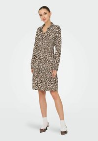 Robe à imprimé léopard avec un col, des manches longues et une jupe à niveaux. Fabriquée en tissu doux avec une coupe décontractée.