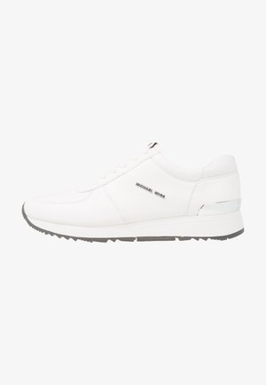 Valge nahkne tennis, millel on sile tekstuur, hall kummist tallaga, seitsme silmaauguga ja hõbedane aksent kanna peal. Logoga külgedel.