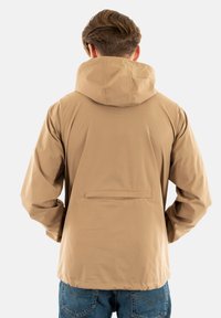 Veste légère beige avec capuche, dotée d'une poche au dos. Texture lisse, poignets élastiques et coupe décontractée, idéale pour les tenues décontractées.