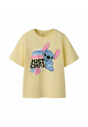 Żółta koszulka z krótkim rękawem z niebieską kreskówkową postacią Stitch z różowymi uszami, kwiatami i napisem "JUST CHILL" pod pasiastym słońcem.