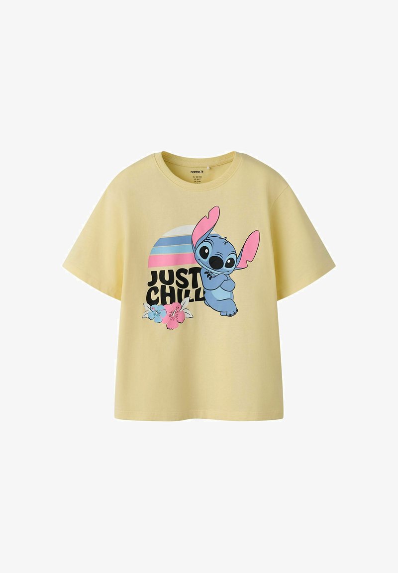 T-shirt jaune à manches courtes avec le personnage de dessin animé bleu Stitch avec des oreilles roses, des fleurs et le texte "JUST CHILL" sous un soleil rayé.