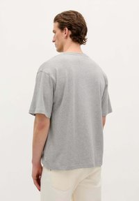 Grijze t-shirt met korte mouwen van katoen, met een relaxed fit, een ronde halslijn en een klein merkembleem aan de onderrand.