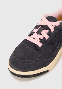 Crne suede tenisice s ružičastim vezicama i mrežastim detaljima. Imaju teksturiranu potplat i meku oblogu, što pruža udobnost i prozračnost.