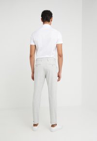 Lichtgrijze, slim-fit broek met een gestructureerde afwerking, met zakken en een tailleband met lussen voor een riem, gecombineerd met een witte short-sleeve shirt.