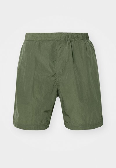 Pantaloni scurți de culoare verde măsliniu dintr-un material ușor, cu textură. Au un brâu elastic și o croială lejeră. Fără buzunare vizibile sau modele.