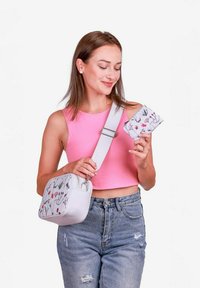 Bílá crossbody taška s květinovým potiskem, zipem na vrchu a nastavitelným popruhem, doplněná o odpovídající peněženku, obě s podrobnými vzory.