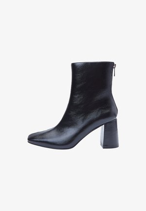 Schwarze Leder-Ankle-Boots mit quadrater Spitze und klobigem Blockabsatz. Sie verfügen über eine glatte, glänzende Textur und einen Reißverschluss auf der Rückseite.