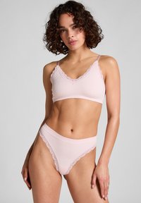 Lichtroze geribbelde bralette met kantafwerking en verstelbare bandjes, gecombineerd met bijpassende kanten slipjes met een gladde afwerking.