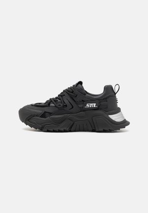 Musta lenkkarit, joissa on muhkea, tekstuurinen muotoilu. Ominaisuuksiin kuuluvat verkkopaneelit, paksut kumipohjat ja hopeinen yksityiskohta kannassa sekä nauhat istuvuutta varten.