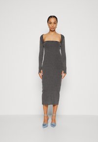 Robe midi grise côtelée avec des manches longues, un décolleté carré et un corps ajusté. Associée à des escarpins pointus bleu clair avec des accents floraux.