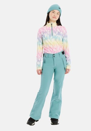 Multicolor langemouwshirt met een halve ritssluiting, met een tie-dye patroon. Gecombineerd met teal skibroeken en zwarte winterlaarzen.