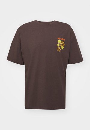 T-shirt marron foncé à manches courtes avec un petit texte japonais jaune et orange ainsi qu'un motif floral sur la partie supérieure gauche de la poitrine.